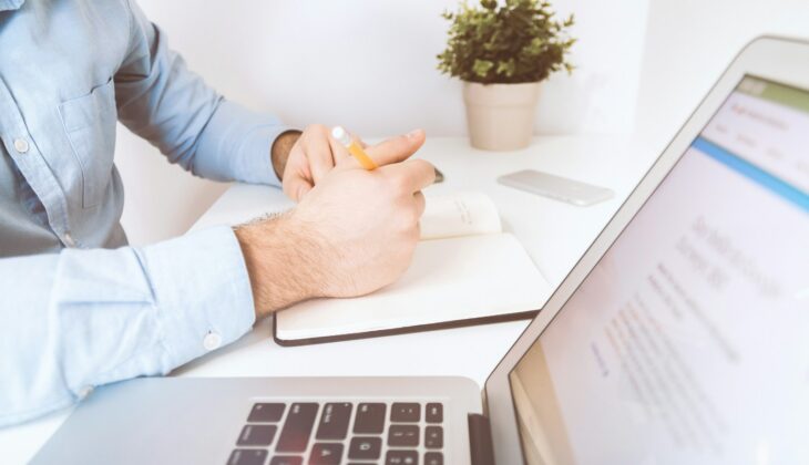 person writing on white notebook