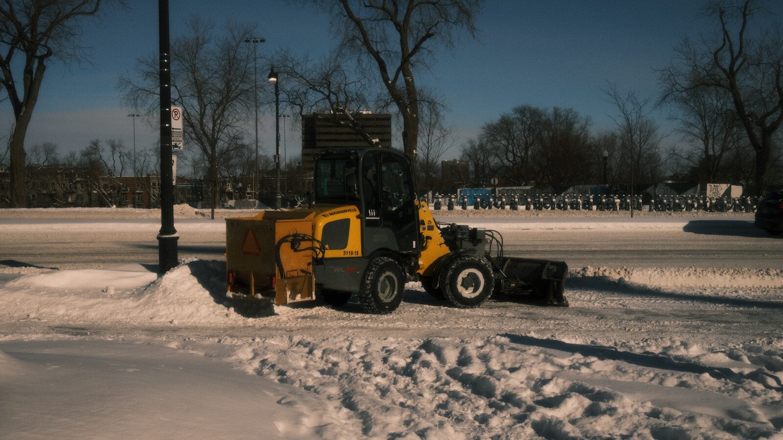 A yellow snowplow clearing snow from a street.